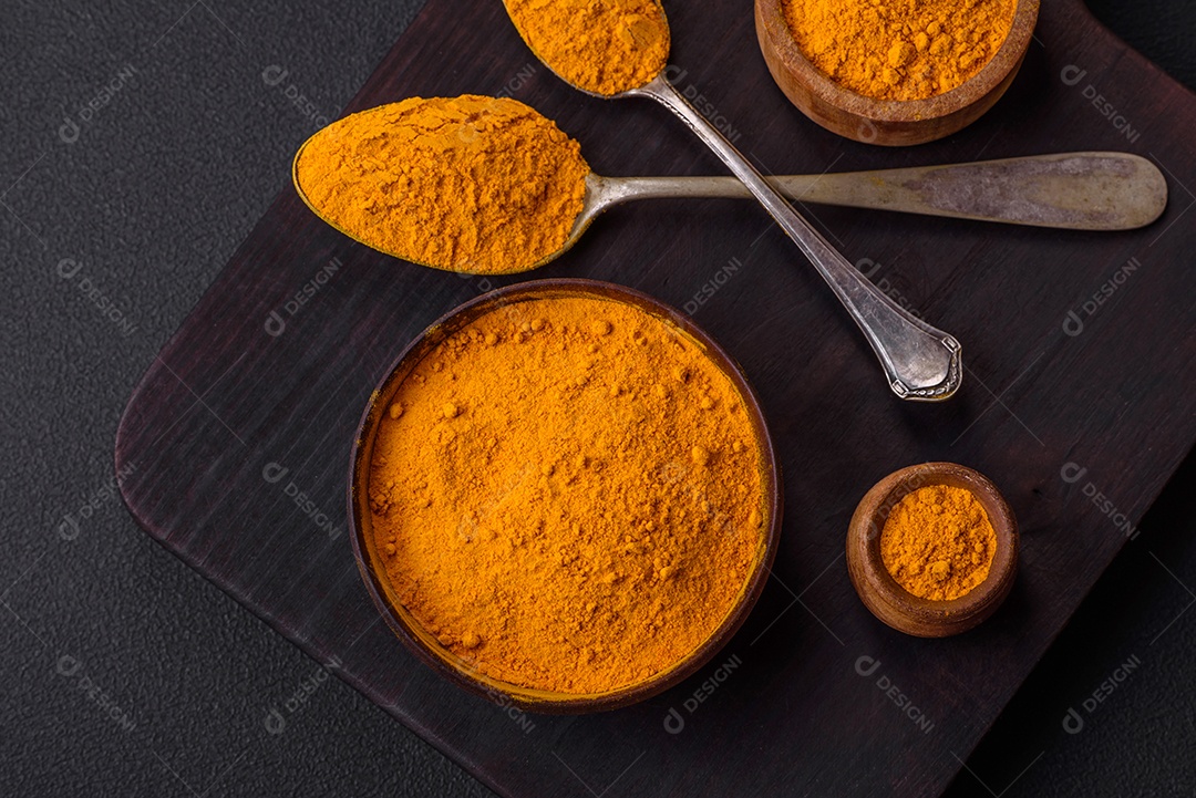 Cúrcuma amarela brilhante ou tempero de curry para preparação de alimentos asiáticos em fundo escuro de concreto