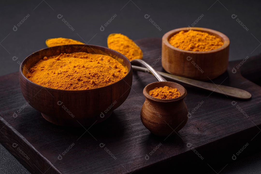 Cúrcuma amarela brilhante ou tempero de curry para preparação de alimentos asiáticos em fundo escuro de concreto