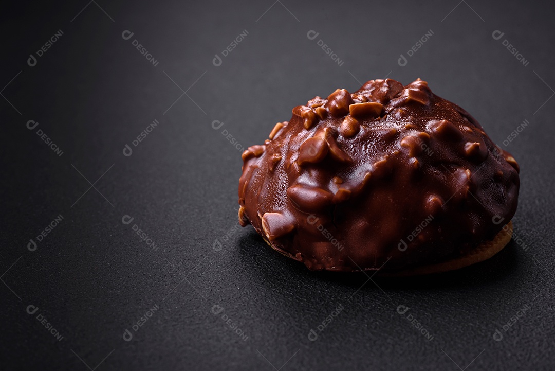 Deliciosa torta de chocolate com nozes em uma placa de cerâmica preta sobre um fundo escuro de concreto
