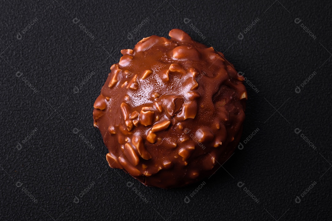 Deliciosa torta de chocolate com nozes em uma placa de cerâmica preta sobre um fundo escuro de concreto