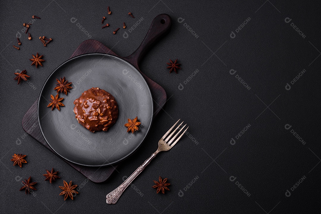 Deliciosa torta de chocolate com nozes em uma placa de cerâmica preta sobre um fundo escuro de concreto