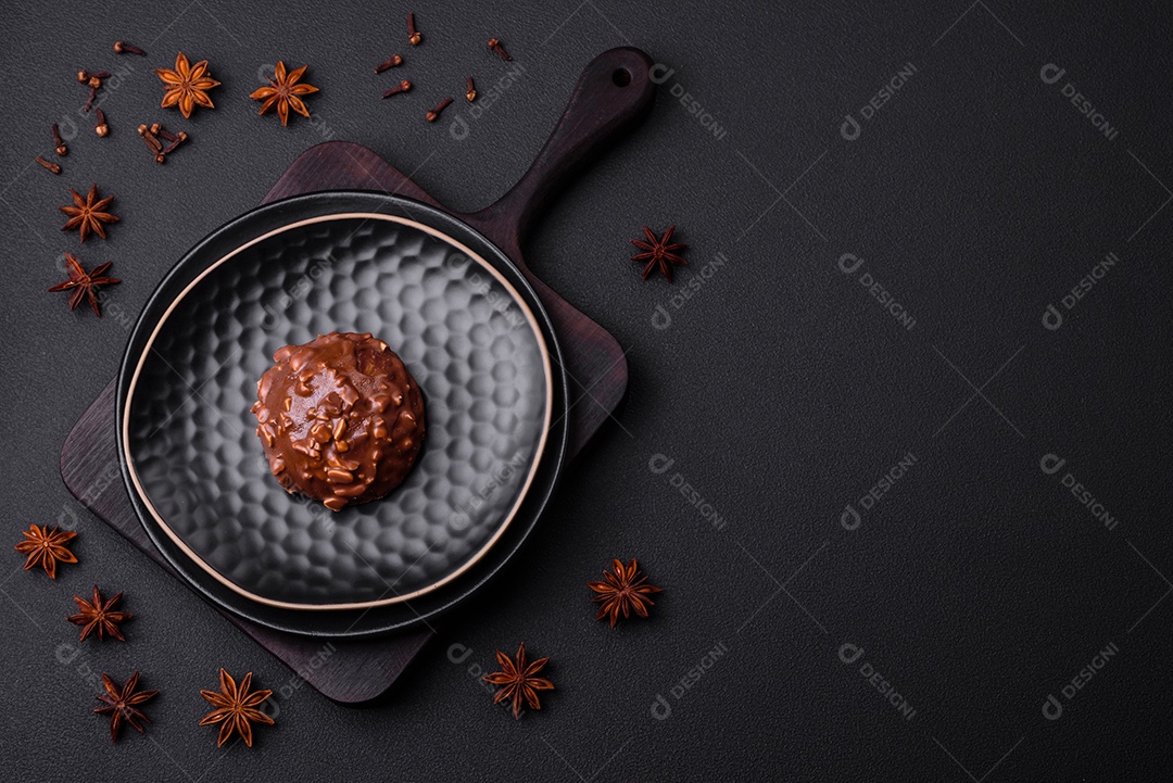 Deliciosa torta de chocolate com nozes em uma placa de cerâmica preta sobre um fundo escuro de concreto