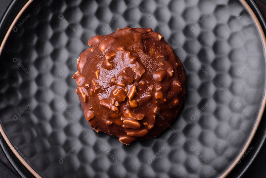 Deliciosa torta de chocolate com nozes em uma placa de cerâmica preta sobre um fundo escuro de concreto