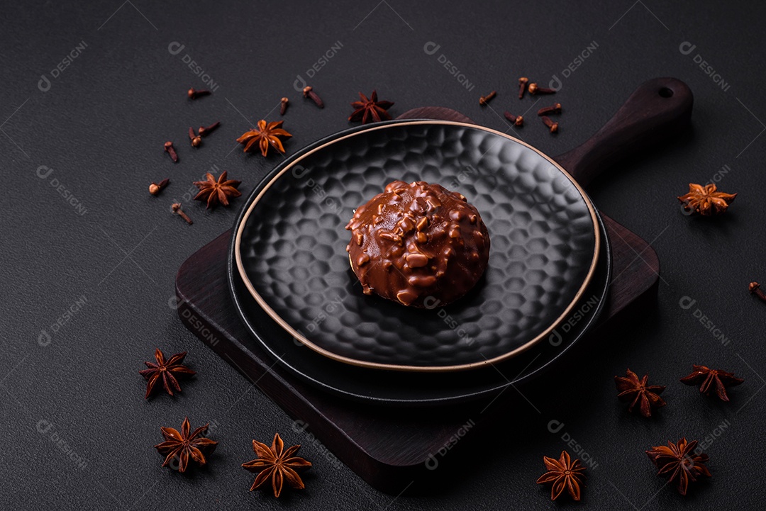 Deliciosa torta de chocolate com nozes em uma placa de cerâmica preta sobre um fundo escuro de concreto