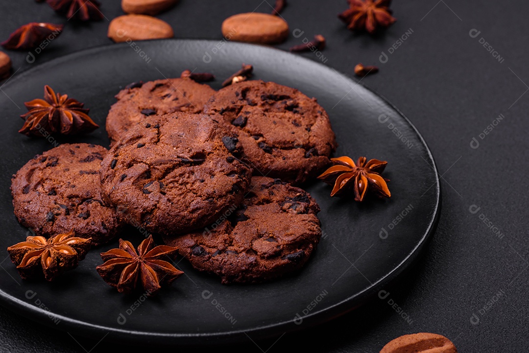 Deliciosos biscoitos de chocolate com nozes em uma placa de cerâmica preta sobre um fundo escuro de concreto