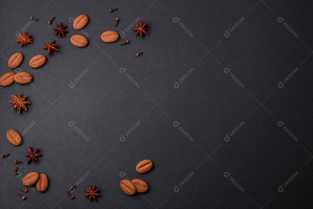 Grãos de café, anis estrelado e cravos da índia sobre fundo isolado escuro.