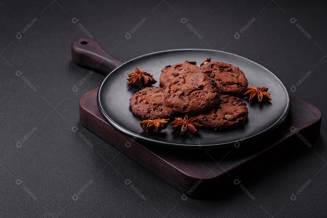Deliciosos biscoitos de chocolate com anis em uma placa de cerâmica preta sobre um fundo escuro de concreto