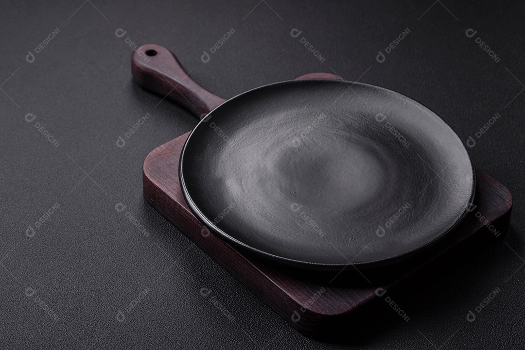 Placa redonda de cerâmica vazia em fundo de concreto texturizado escuro, preparação para o jantar