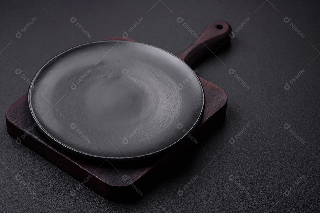 Placa redonda de cerâmica vazia em fundo de concreto texturizado escuro, preparação para o jantar