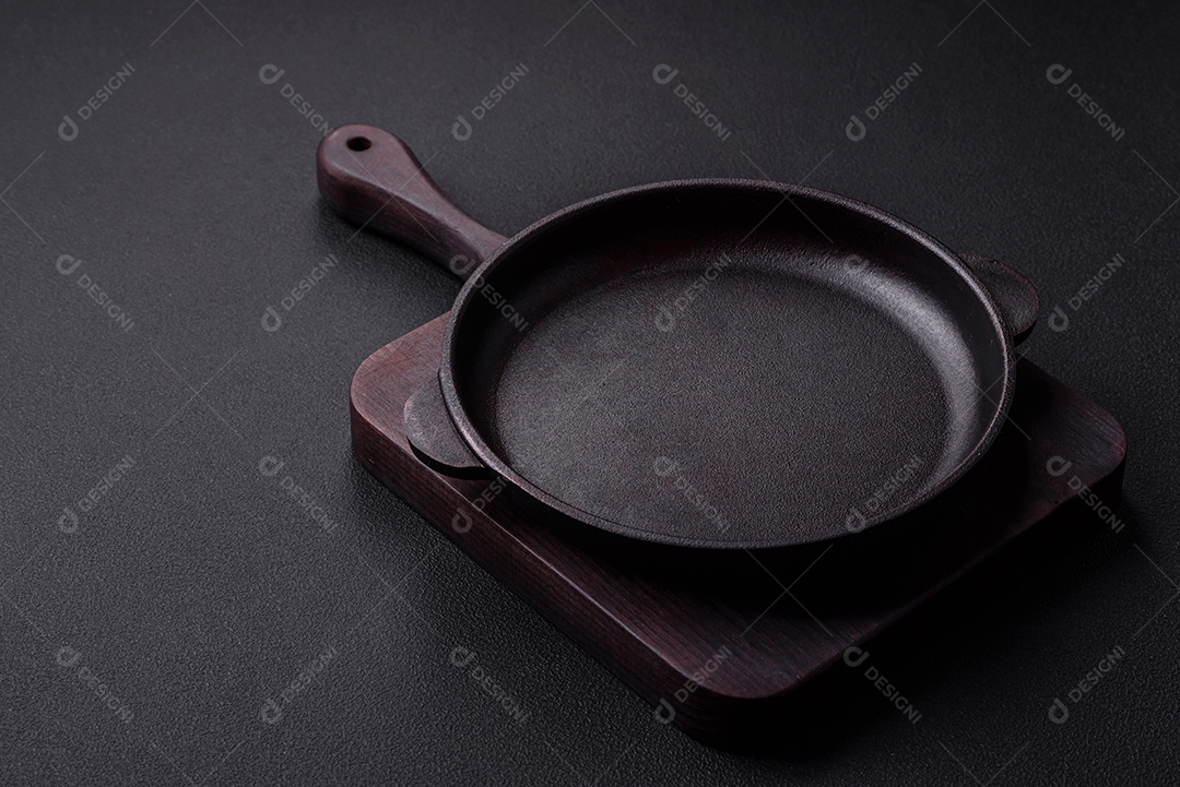 Frigideira redonda vazia de ferro fundido em fundo de concreto texturizado escuro, preparação para o jantar
