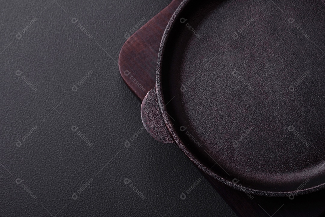 Frigideira redonda vazia de ferro fundido em fundo de concreto texturizado escuro, preparação para o jantar