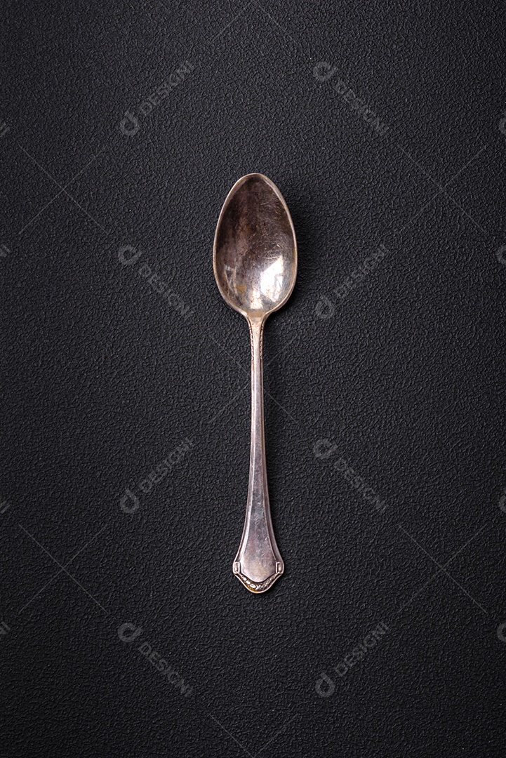 Colher de metal vazia em fundo de concreto texturizado escuro. Talheres, preparação para o jantar