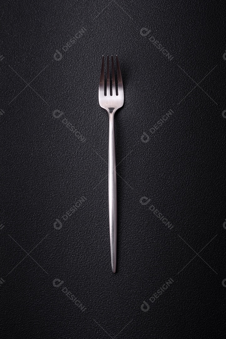 Garfo de cozinha de metal em um fundo de concreto texturizado escuro. Talheres, preparação para o jantar