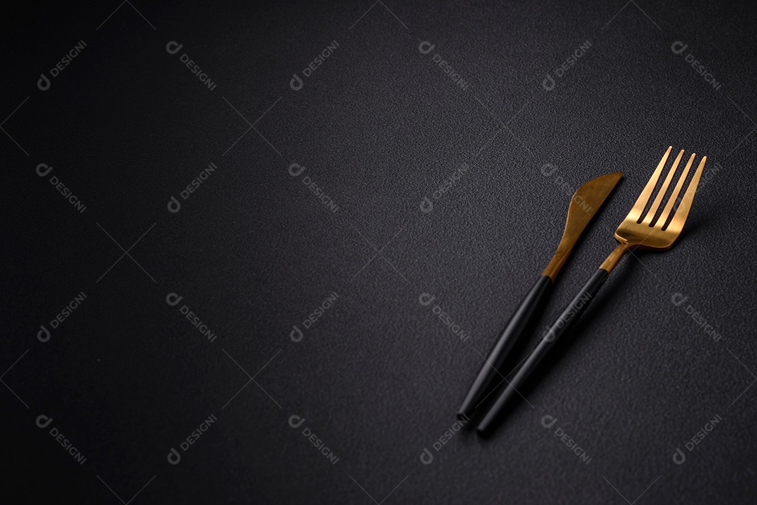Faca e garfo de cozinha de metal em um fundo de concreto texturizado escuro. Talheres, preparação para o jantar