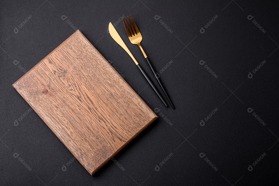 Tábua de corte de madeira vazia em fundo de concreto texturizado escuro. Talheres, preparação para o jantar