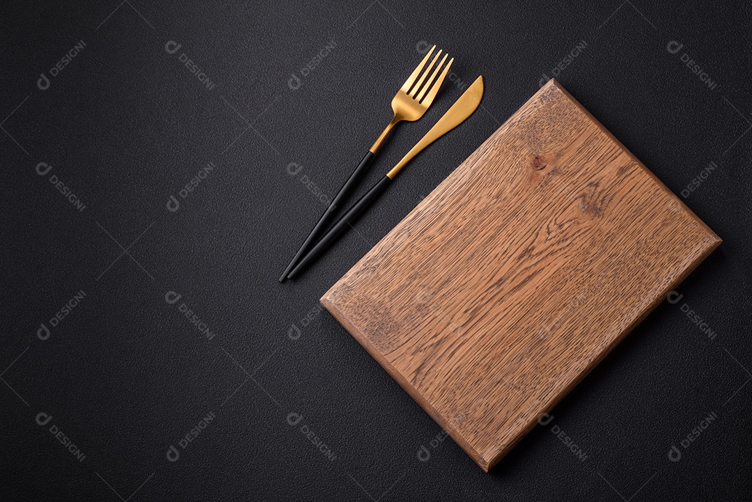 Tábua de corte de madeira vazia em fundo de concreto texturizado escuro. Talheres, preparação para o jantar