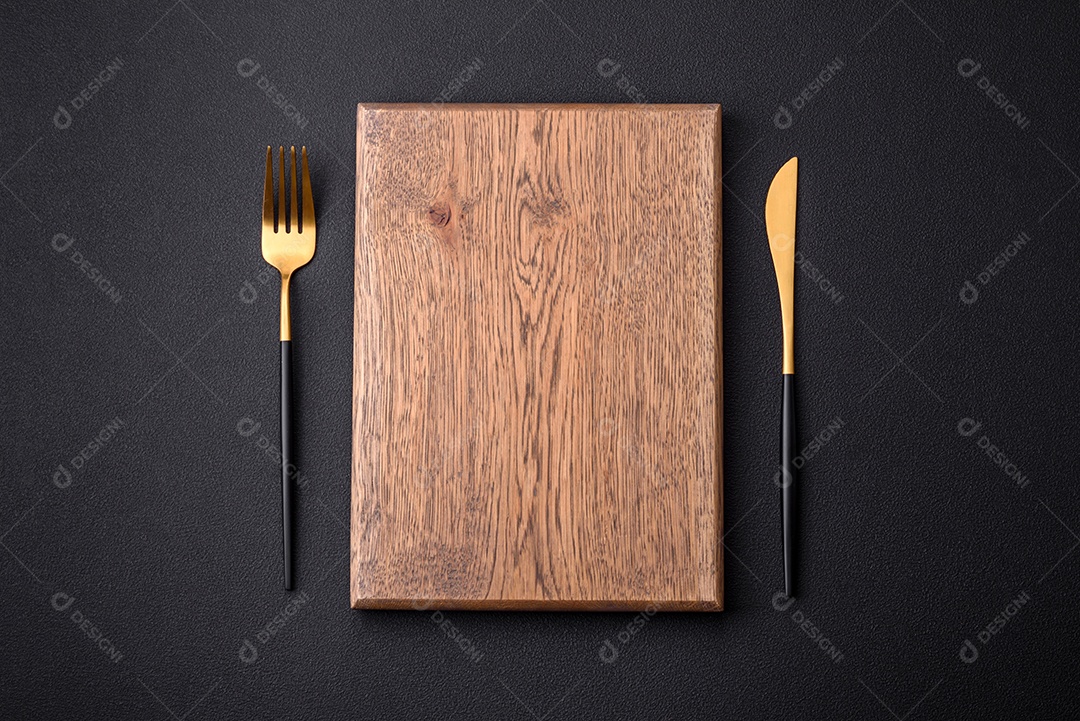 Tábua de corte de madeira vazia em fundo de concreto texturizado escuro. Talheres, preparação para o jantar