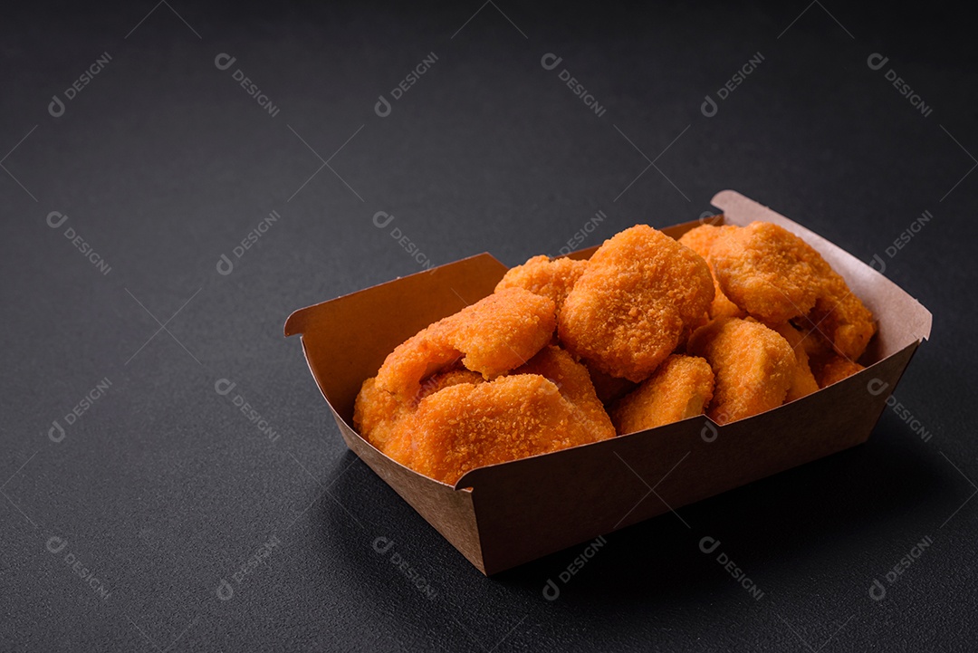 Deliciosos nuggets de frango crocantes frescos em um fundo escuro de concreto. Alimentos não saudáveis, fast food