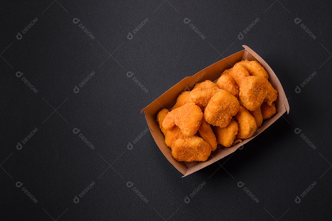 Deliciosos nuggets de frango crocantes frescos em um fundo escuro de concreto. Alimentos não saudáveis, fast food