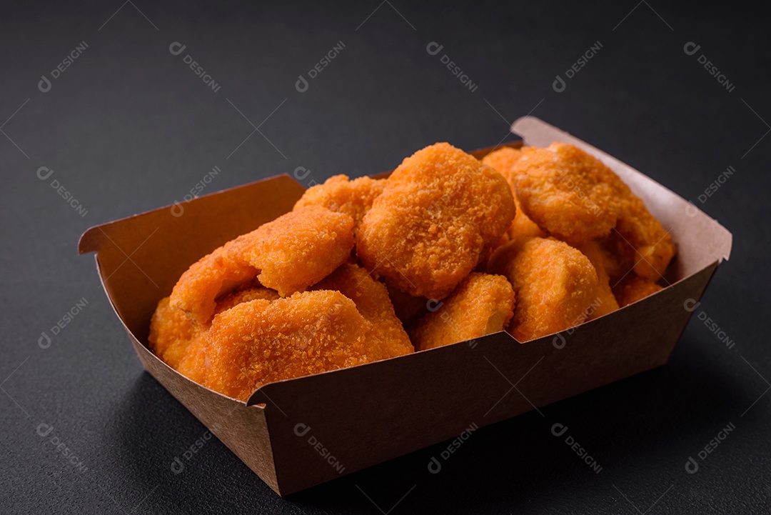 Deliciosos nuggets de frango crocantes frescos em um fundo escuro de concreto. Alimentos não saudáveis, fast food