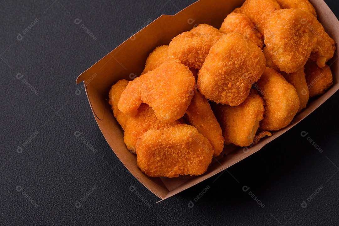 Deliciosos nuggets de frango crocantes frescos em um fundo escuro de concreto. Alimentos não saudáveis, fast food