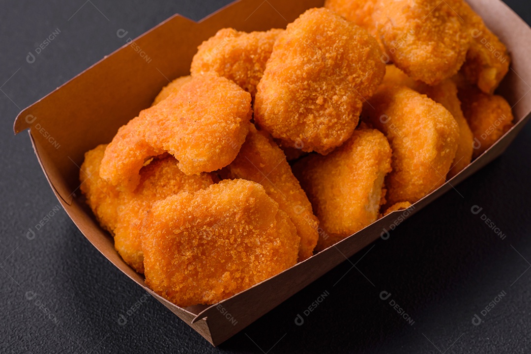 Deliciosos nuggets de frango crocantes frescos em um fundo escuro de concreto. Alimentos não saudáveis, fast food