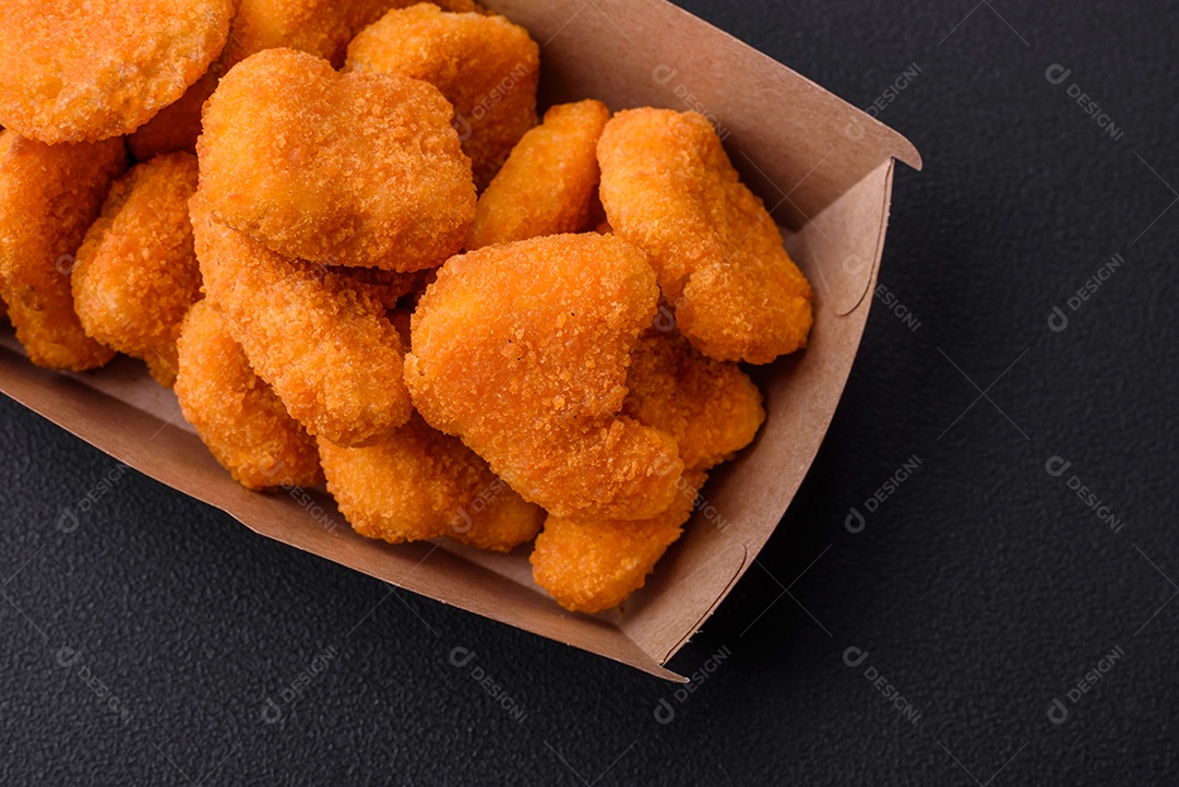 Deliciosos nuggets de frango crocantes frescos em um fundo escuro de concreto. Alimentos não saudáveis, fast food