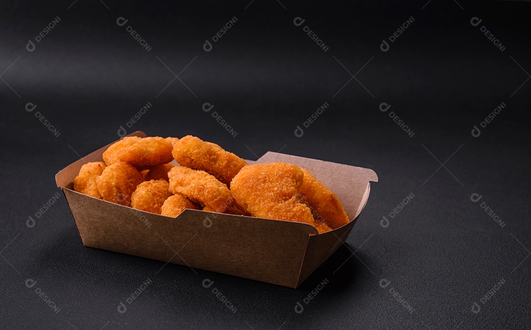 Deliciosos nuggets de frango crocantes frescos em um fundo escuro de concreto. Alimentos não saudáveis, fast food
