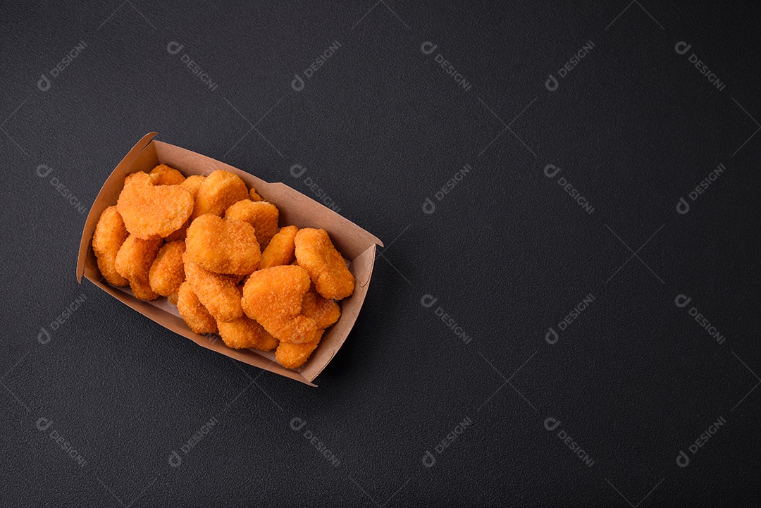 Deliciosos nuggets de frango crocantes frescos em um fundo escuro de concreto. Alimentos não saudáveis, fast food