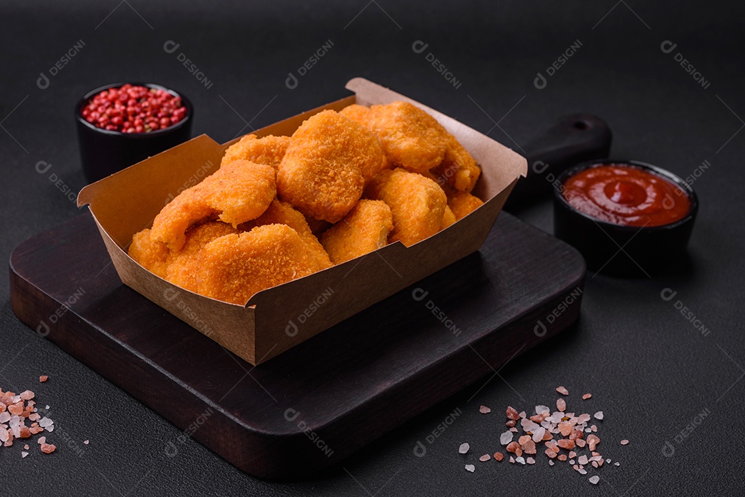 Deliciosos nuggets de frango crocantes frescos em um fundo escuro de concreto. Alimentos não saudáveis, fast food