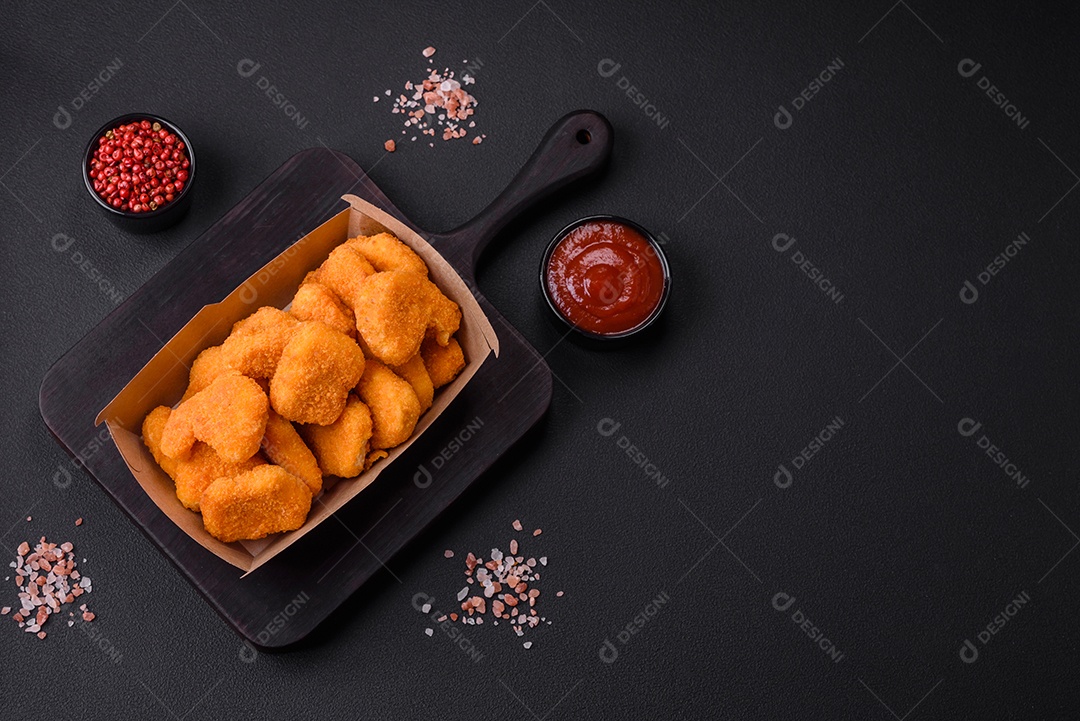 Deliciosos nuggets de frango crocantes frescos em um fundo escuro de concreto. Alimentos não saudáveis, fast food