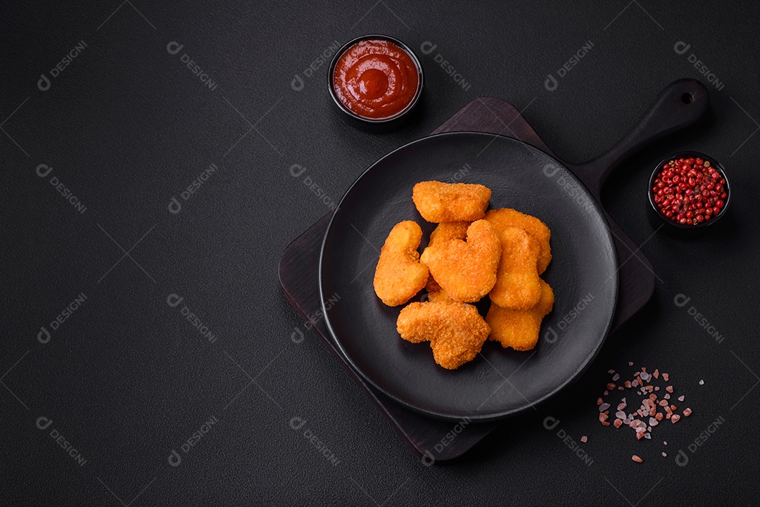 Deliciosos nuggets de frango crocantes frescos em um fundo escuro de concreto. Alimentos não saudáveis, fast food