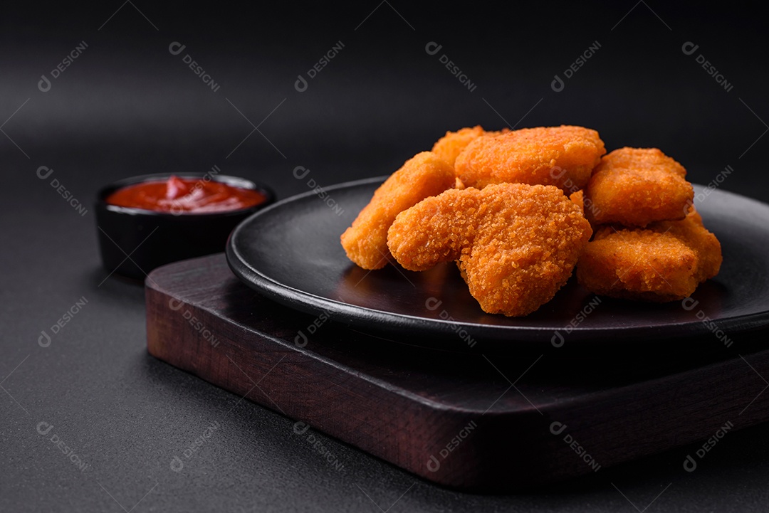 Deliciosos nuggets de frango crocantes frescos em um fundo escuro de concreto. Alimentos não saudáveis, fast food