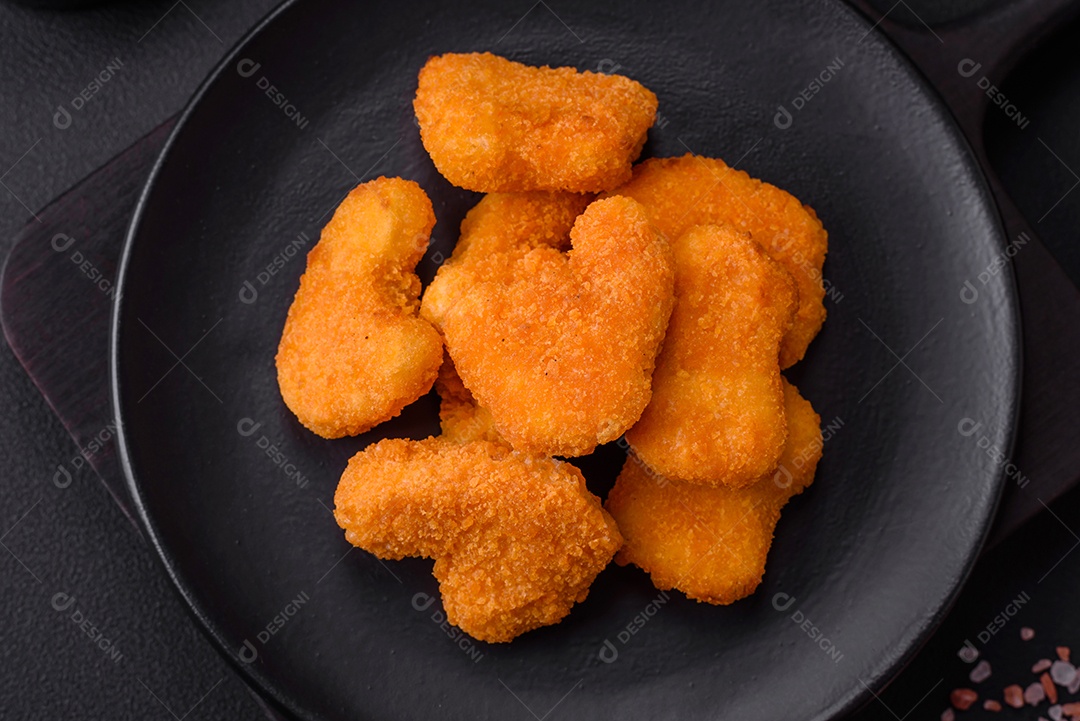 Deliciosos nuggets de frango crocantes frescos em um fundo escuro de concreto. Alimentos não saudáveis, fast food
