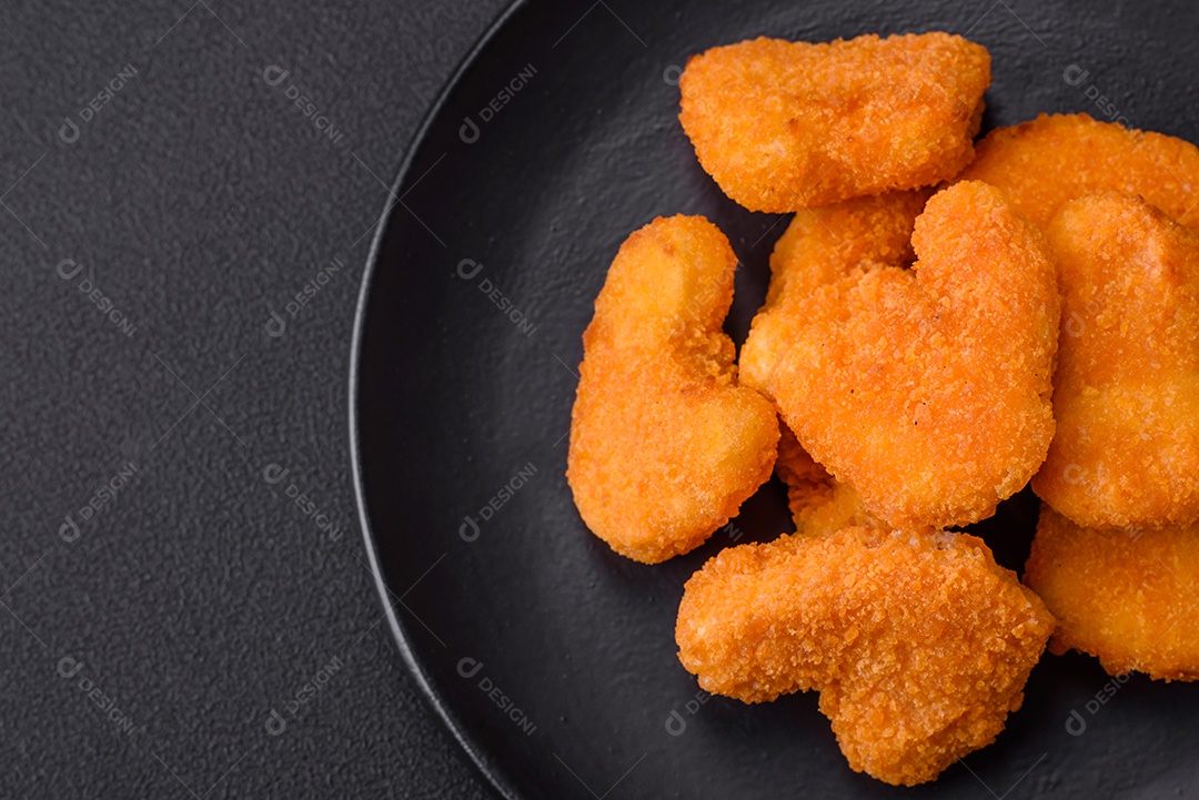 Deliciosos nuggets de frango crocantes frescos em um fundo escuro de concreto. Alimentos não saudáveis, fast food