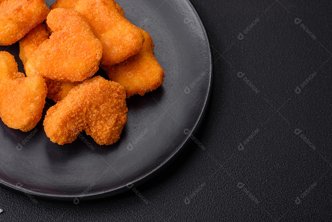 Deliciosos nuggets de frango crocantes frescos em um fundo escuro de concreto. Alimentos não saudáveis, fast food