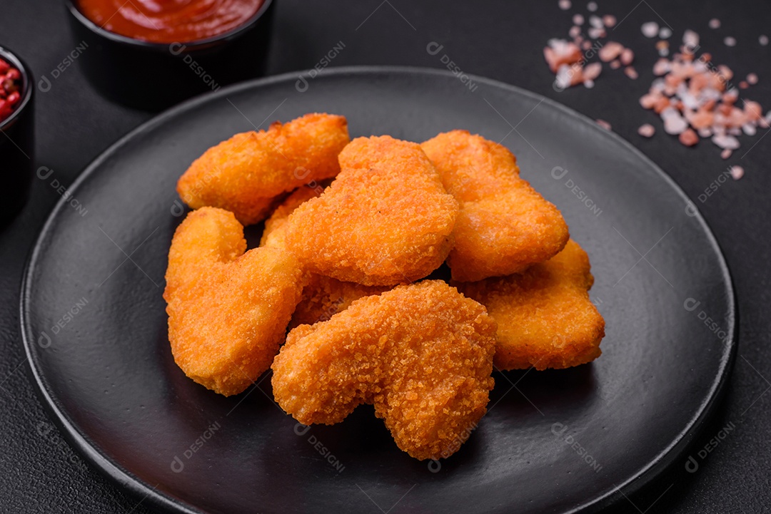 Deliciosos nuggets de frango crocantes frescos em um fundo escuro de concreto. Alimentos não saudáveis, fast food