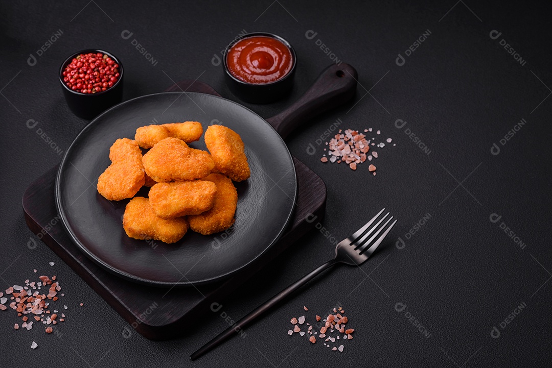 Deliciosos nuggets de frango crocantes frescos em um fundo escuro de concreto. Alimentos não saudáveis, fast food