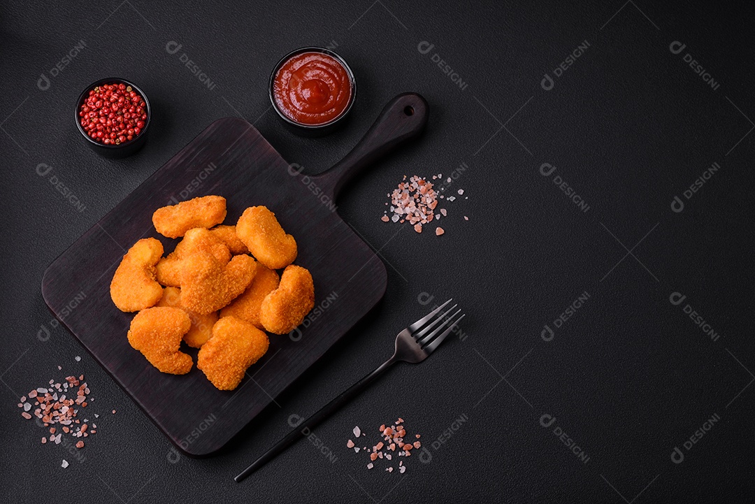 Deliciosos nuggets de frango crocantes frescos em um fundo escuro de concreto. Alimentos não saudáveis, fast food