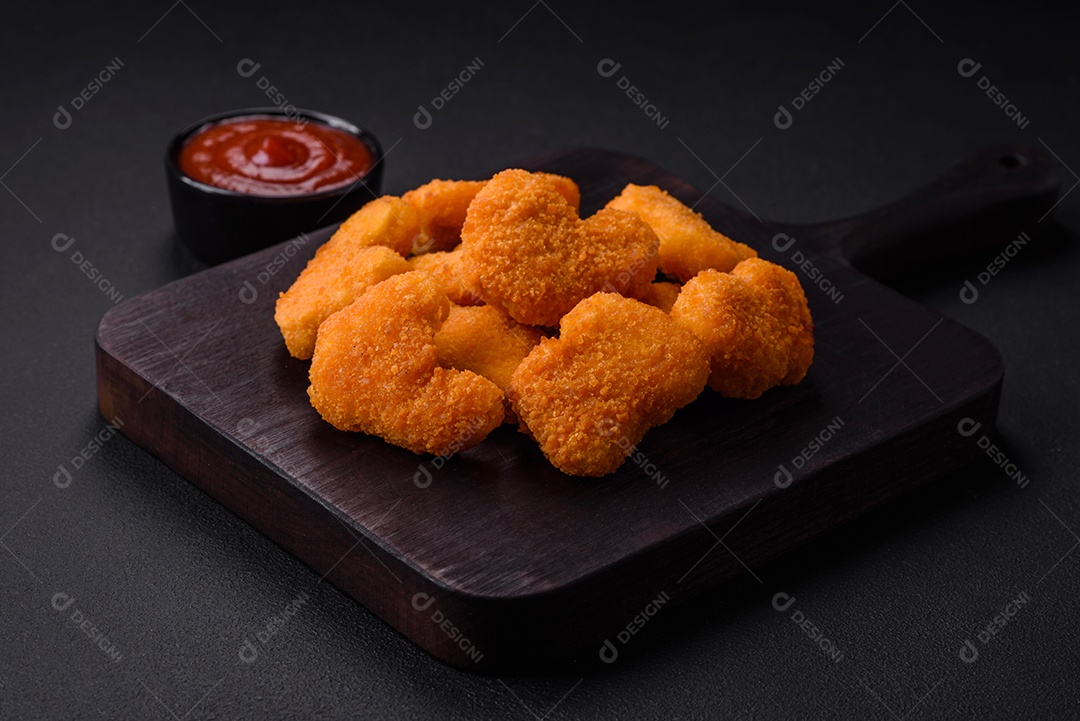Deliciosos nuggets de frango crocantes frescos em um fundo escuro de concreto. Alimentos não saudáveis, fast food