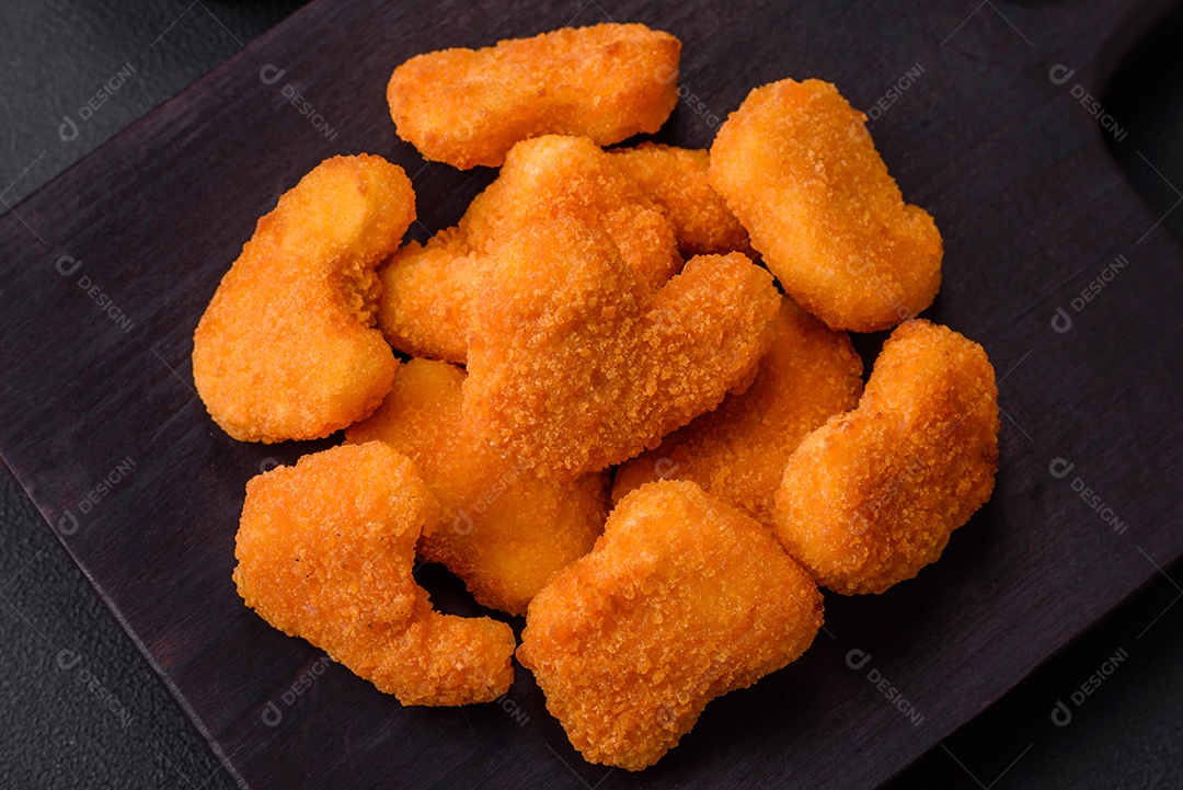 Deliciosos nuggets de frango crocantes frescos em um fundo escuro de concreto. Alimentos não saudáveis, fast food