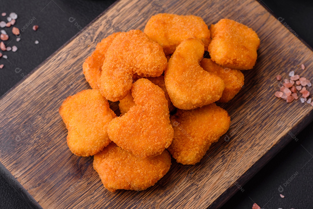 Deliciosos nuggets de frango crocantes frescos em um fundo escuro de concreto. Alimentos não saudáveis, fast food