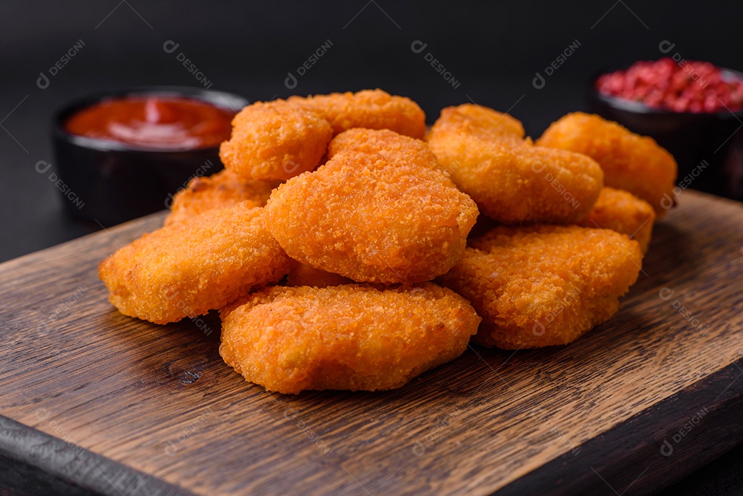 Deliciosos nuggets de frango crocantes frescos em um fundo escuro de concreto. Alimentos não saudáveis, fast food