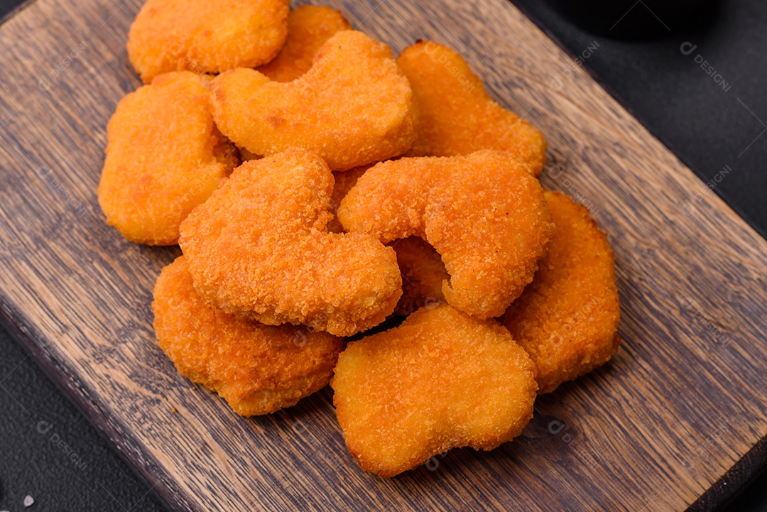 Deliciosos nuggets de frango crocantes frescos em um fundo escuro de concreto. Alimentos não saudáveis, fast food