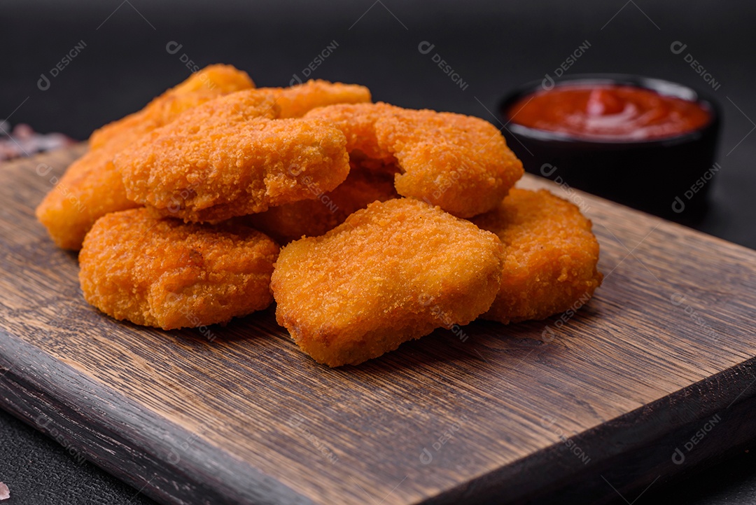 Deliciosos nuggets de frango crocantes frescos em um fundo escuro de concreto. Alimentos não saudáveis, fast food