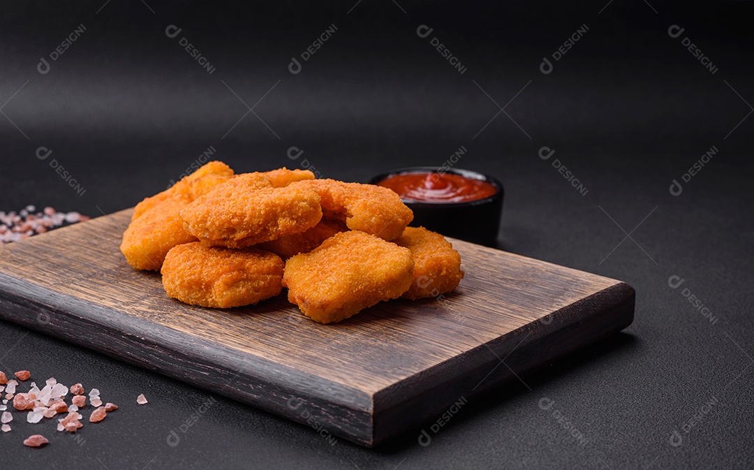 Deliciosos nuggets de frango crocantes frescos em um fundo escuro de concreto. Alimentos não saudáveis, fast food