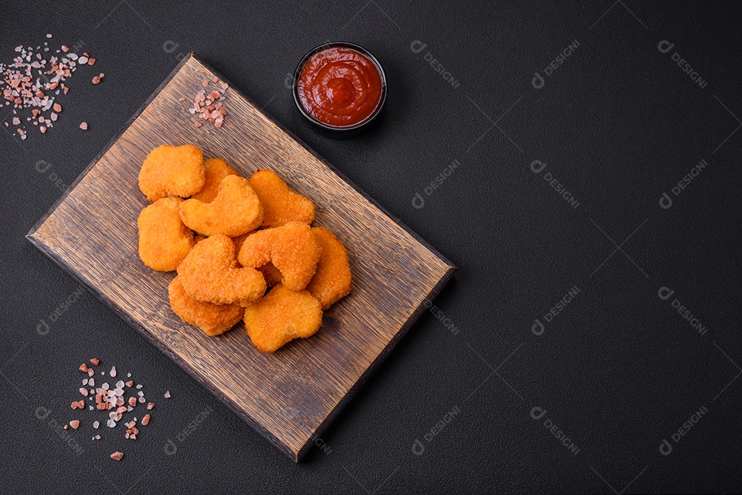 Deliciosos nuggets de frango crocantes frescos em um fundo escuro de concreto. Alimentos não saudáveis, fast food