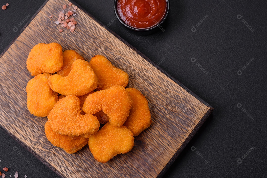 Deliciosos nuggets de frango crocantes frescos em um fundo escuro de concreto. Alimentos não saudáveis, fast food