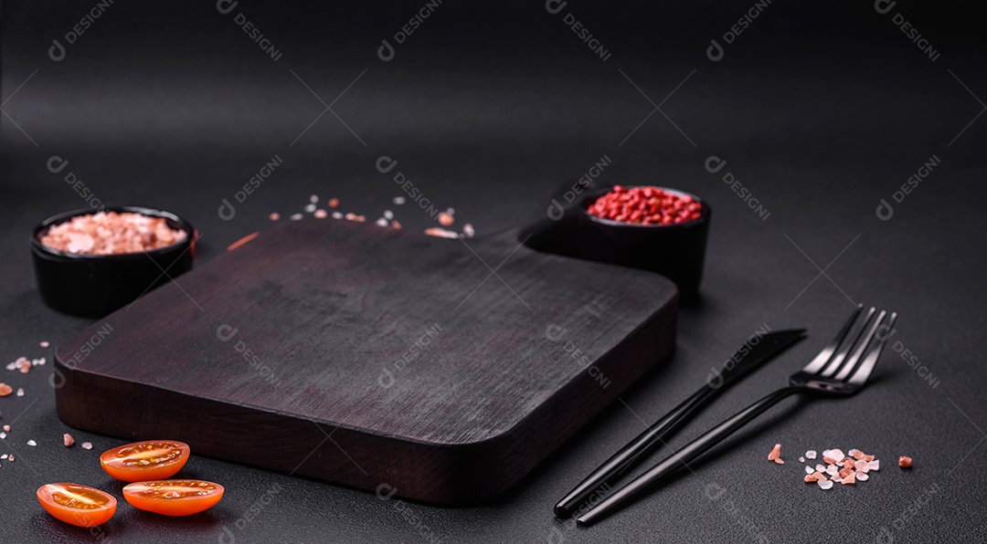 Tábua de corte de madeira vazia em fundo de concreto texturizado escuro. Talheres, preparação para o jantar