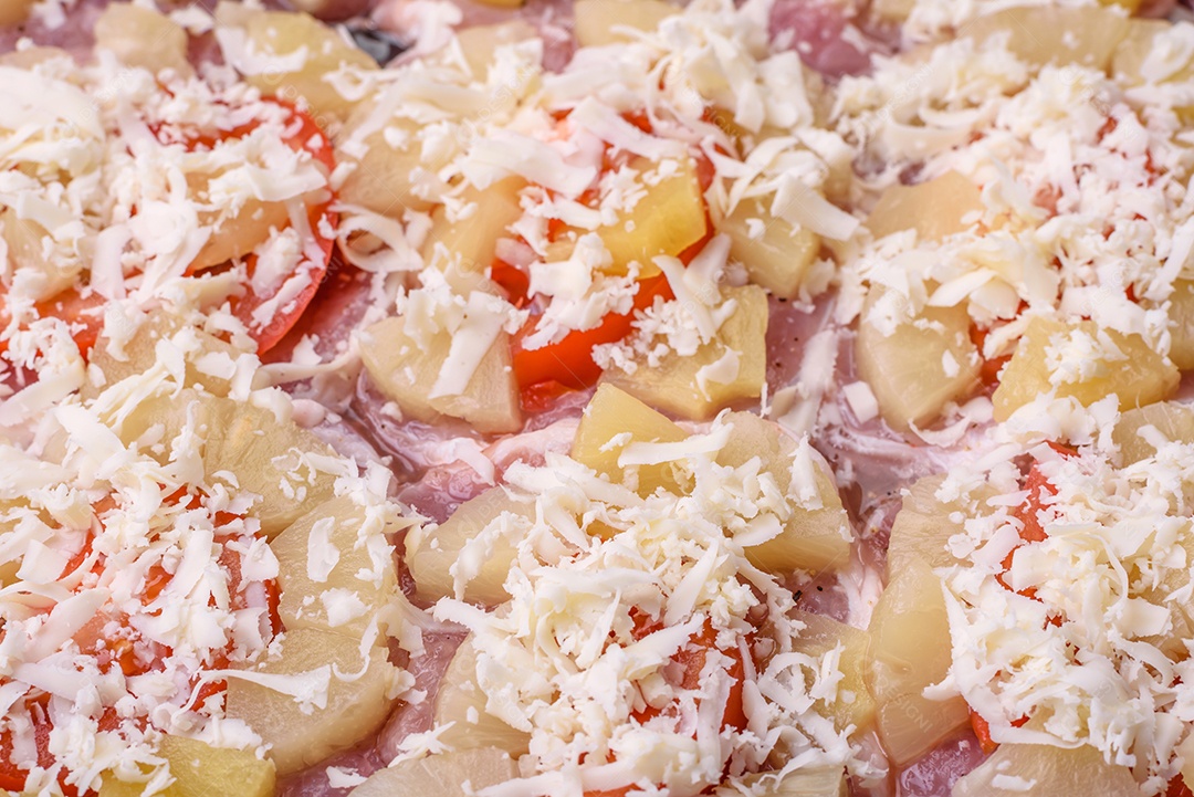Um prato composto por carne, tomate, abacaxi, queijo, especiarias e ervas em pergaminho em uma assadeira. Preparando alimentos para assar no forno